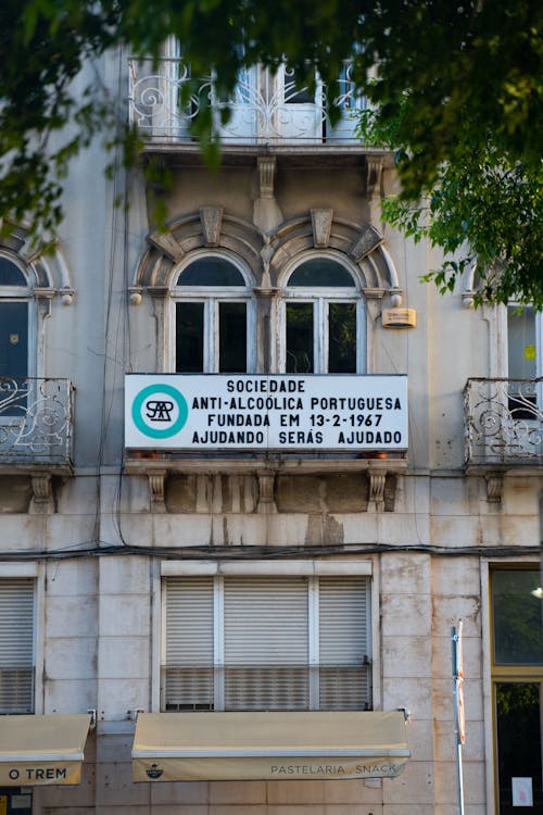 Exterior of a Traditional Building in City with a Sign Hanging on a Balcony 