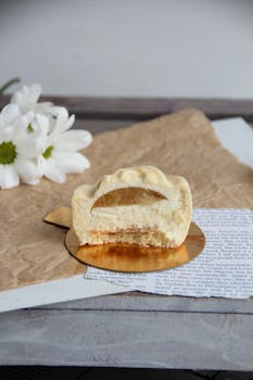 Elegant cream-filled pastry on parchment with daisies in the backdrop.
