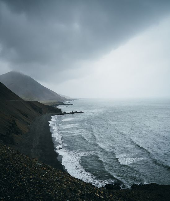 A moody seascape with black sand beach and dramatic clouds in Iceland.