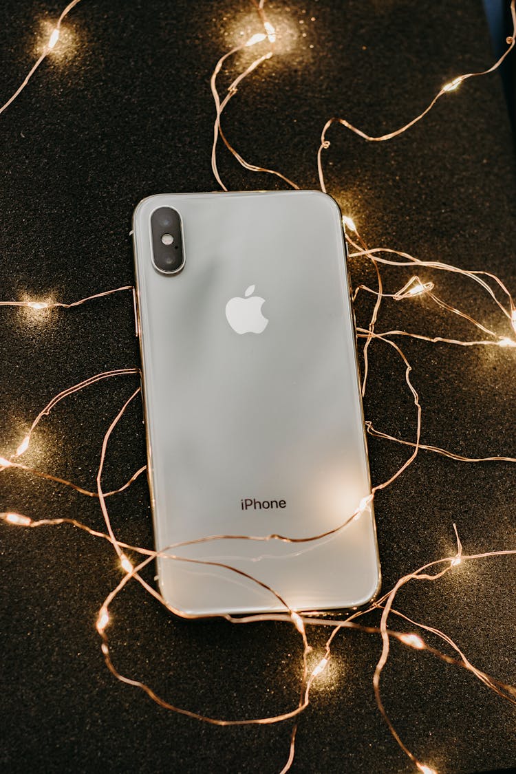 Silver Iphone X Lying On Pre-lit String Lights