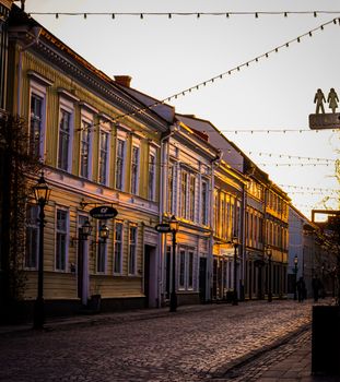 Sunlit cobblestone street with vintage buildings and string lights capturing a serene evening ambiance.
