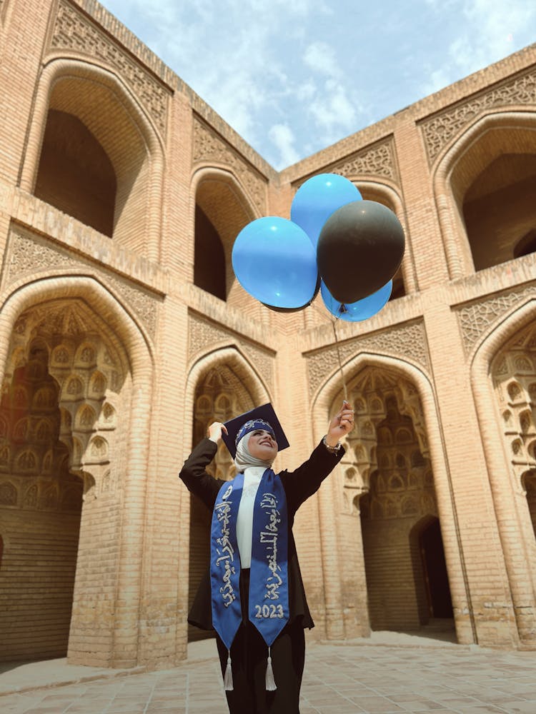 Woman In Graduation Gown Holding Balloons 