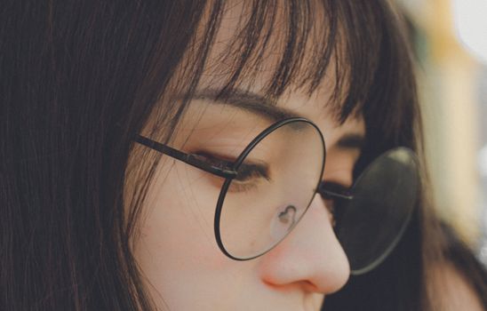 特写镜头细致地捕捉了一名戴着圆眼镜的年轻女子