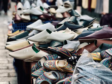 A vibrant selection of Moroccan slippers displayed at an outdoor market stall.