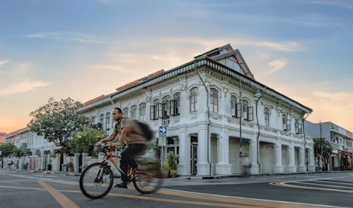 A Cyclist on a Street in front of the Peranakan Houses in Singapore 