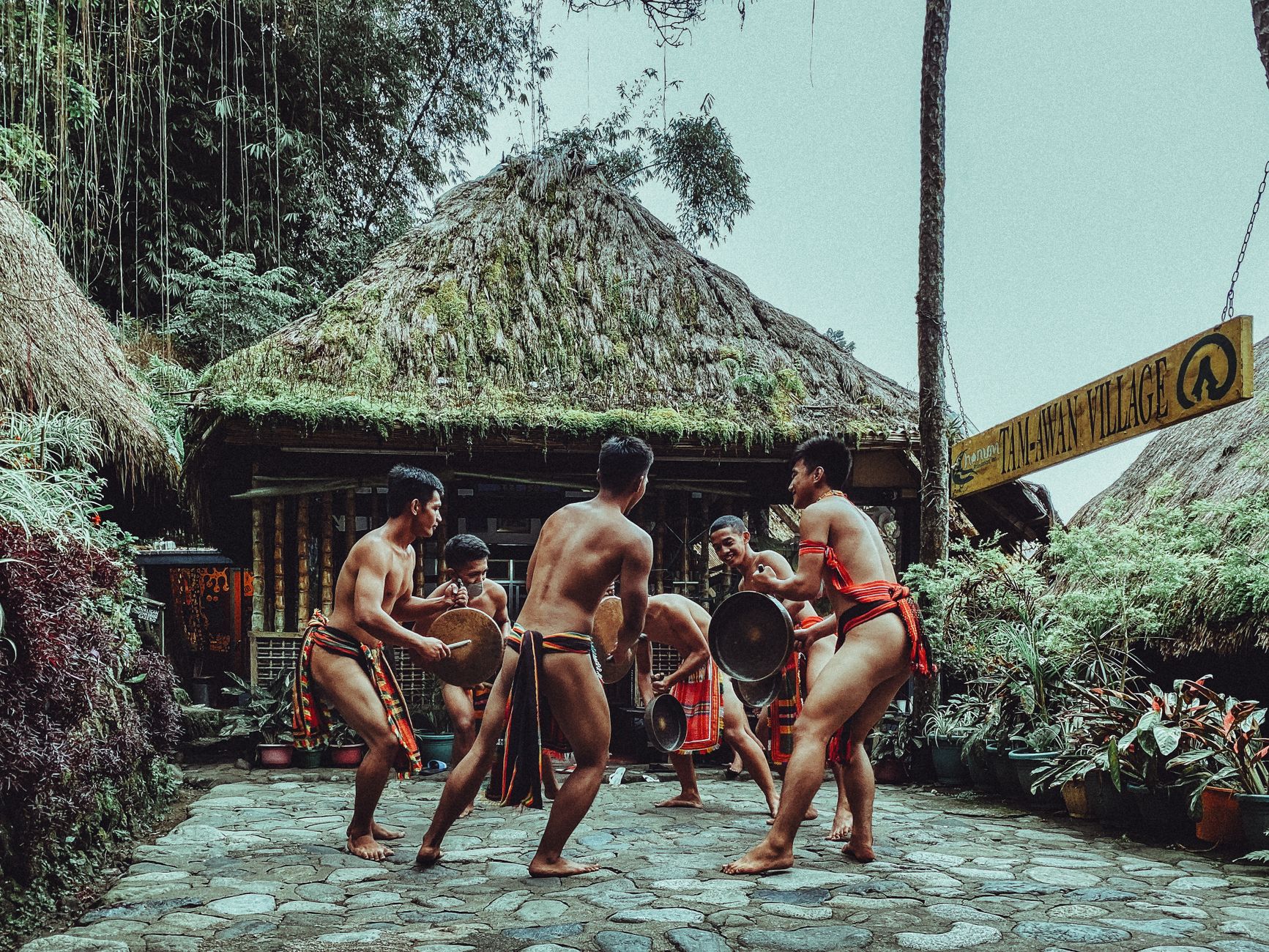 A traditional cockfighting arena in the Philippines at dawn, spectators gathered quietly around a wooden ring