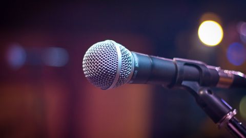 Dynamic microphone on stand with blurred stage lights in background.