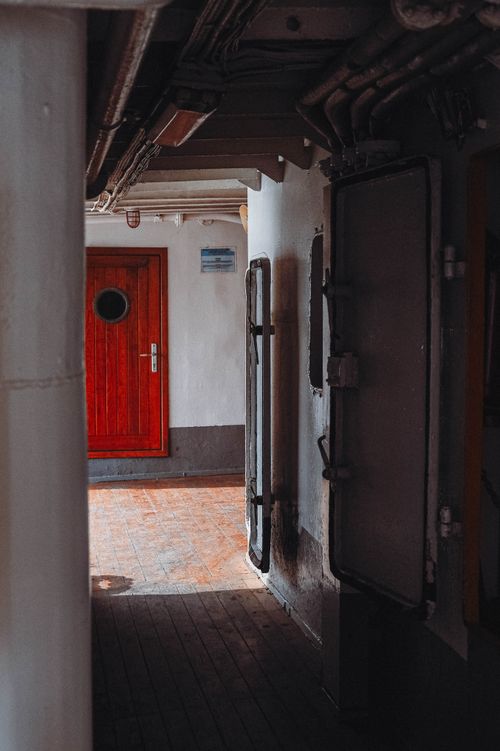 Free A dimly lit marine corridor featuring a prominent red door. Stock Photo