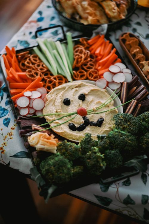 Free A colorful vegetable snack tray arranged to resemble an animal face with hummus and veggies. Stock Photo