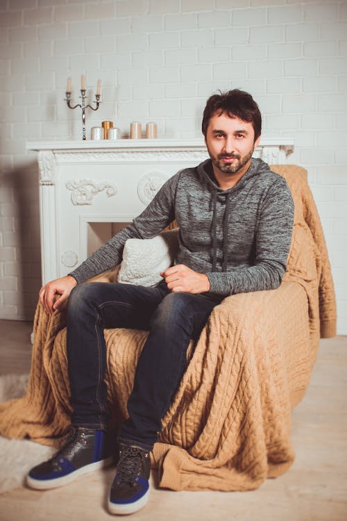 Photo of a Man Sitting on a Brown Chair 