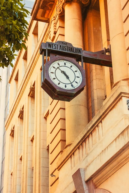 A clock on the side of a building with a building in the background