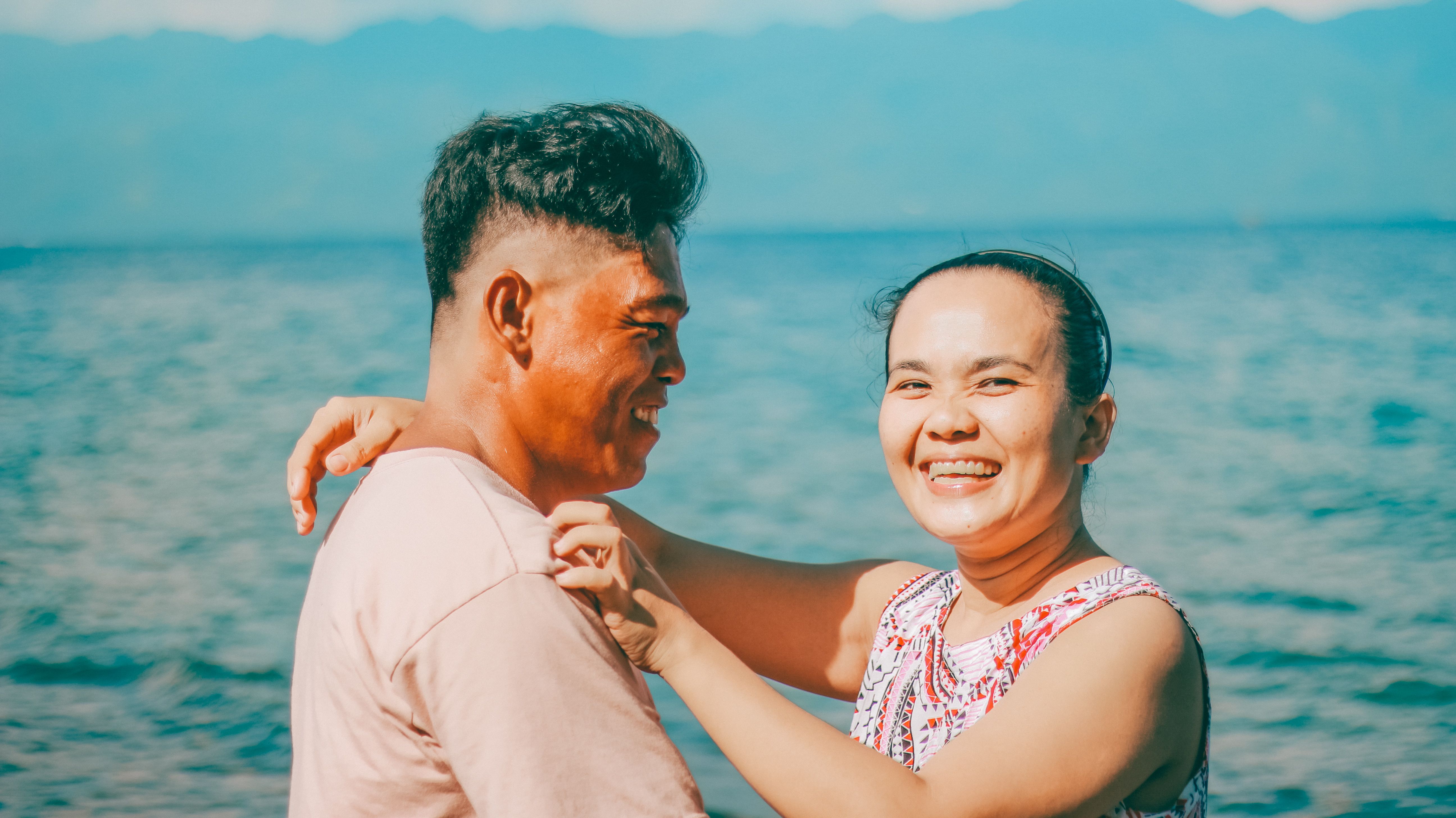 Happy couple sharing a moment by the ocean, embracing their love and connection.