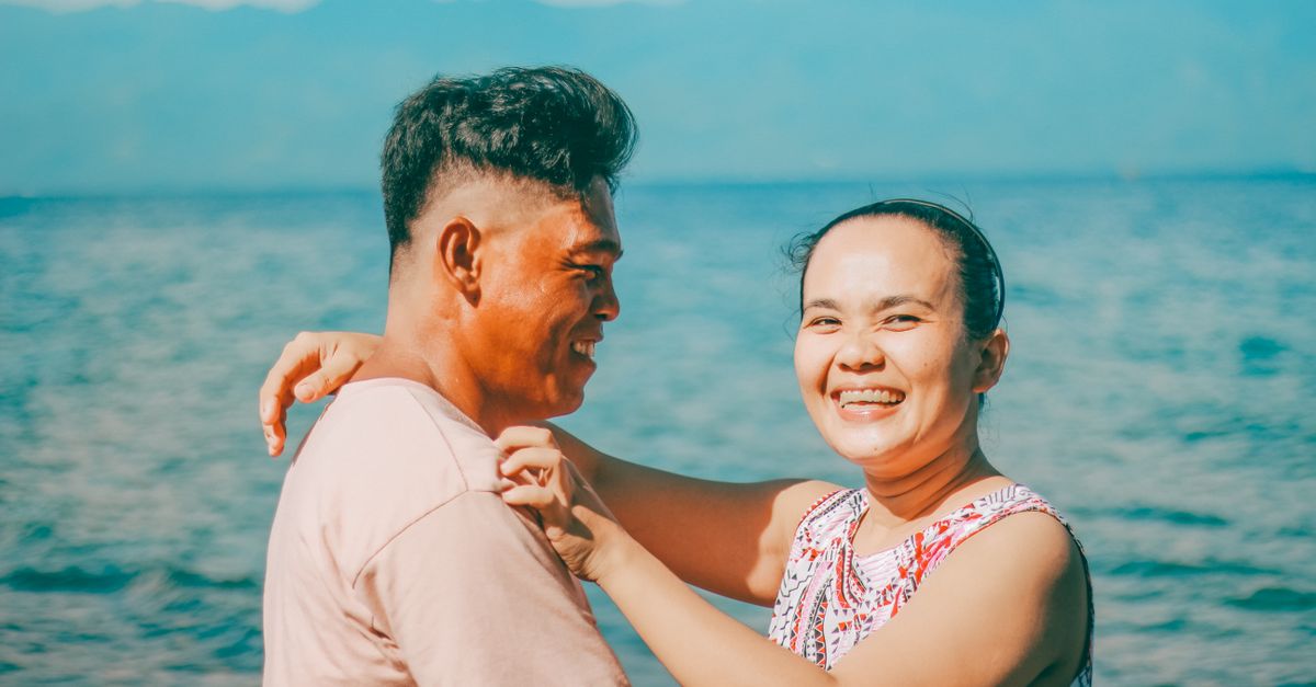 Happy couple sharing a moment by the ocean, embracing their love and connection.