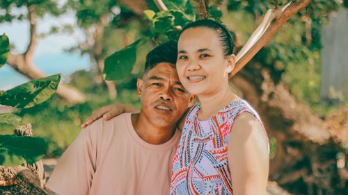 Free Smiling couple enjoying a sunny summer day in a lush forest setting. Stock Photo