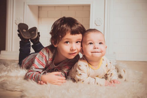 Jongen Die Naast Baby Op Mat Ligt