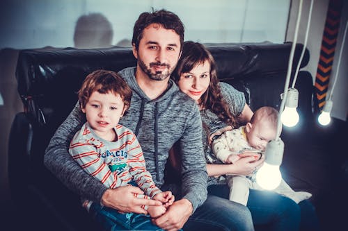 Free Man and Woman Carrying Babies While Sitting on Chair Stock Photo