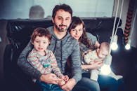 一家四口在室内沙发上快乐地坐着，脸上带着微笑