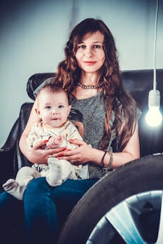 一幅温馨的室内肖像，描绘了一位母亲怀抱着她的孩子，柔和温暖的灯光映照着他们