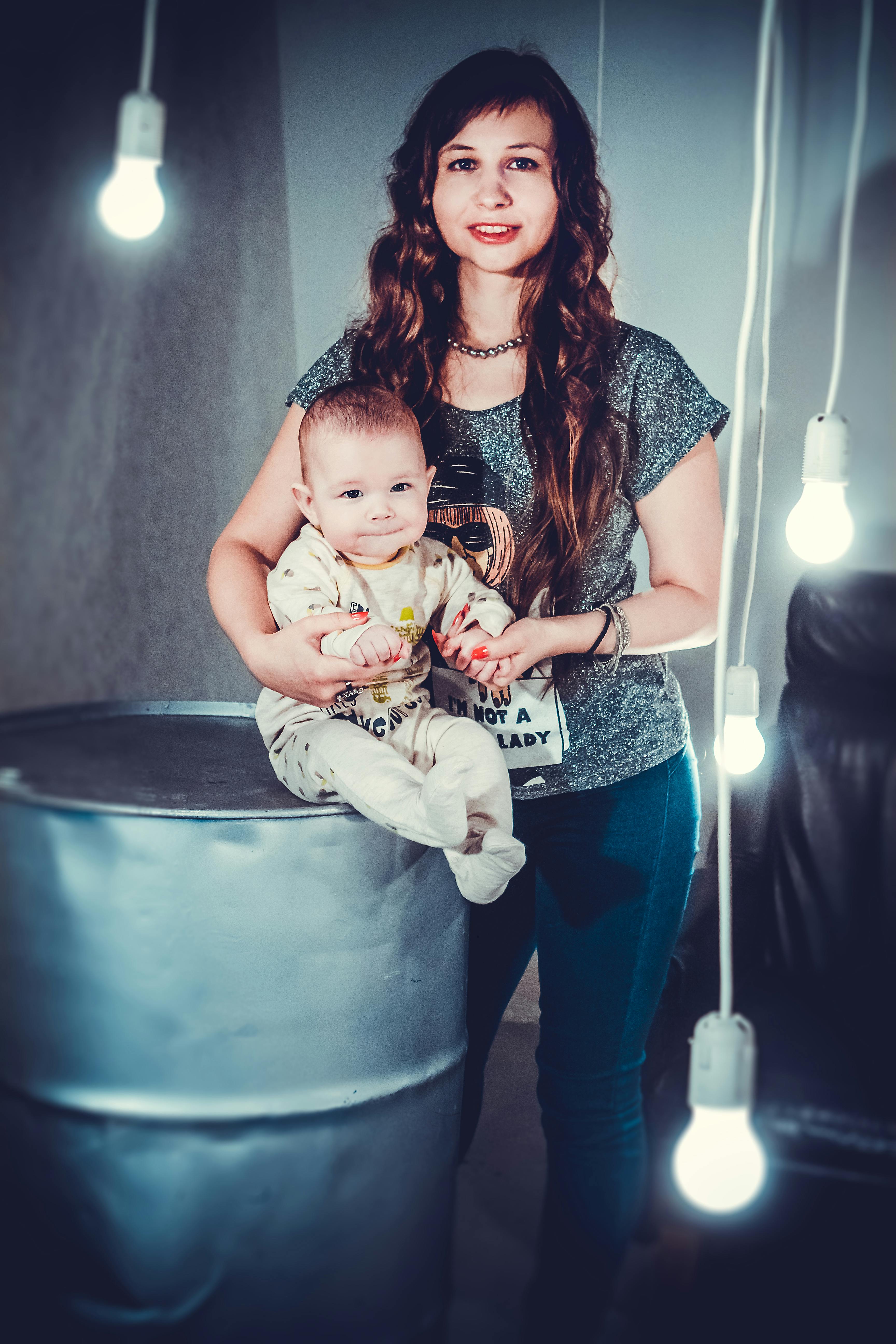 A mother lovingly holding her baby in a modern indoor space with hanging lights.