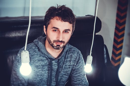 一名身穿连帽衫的男子被悬挂的灯泡照亮，营造出喜怒无常的氛围