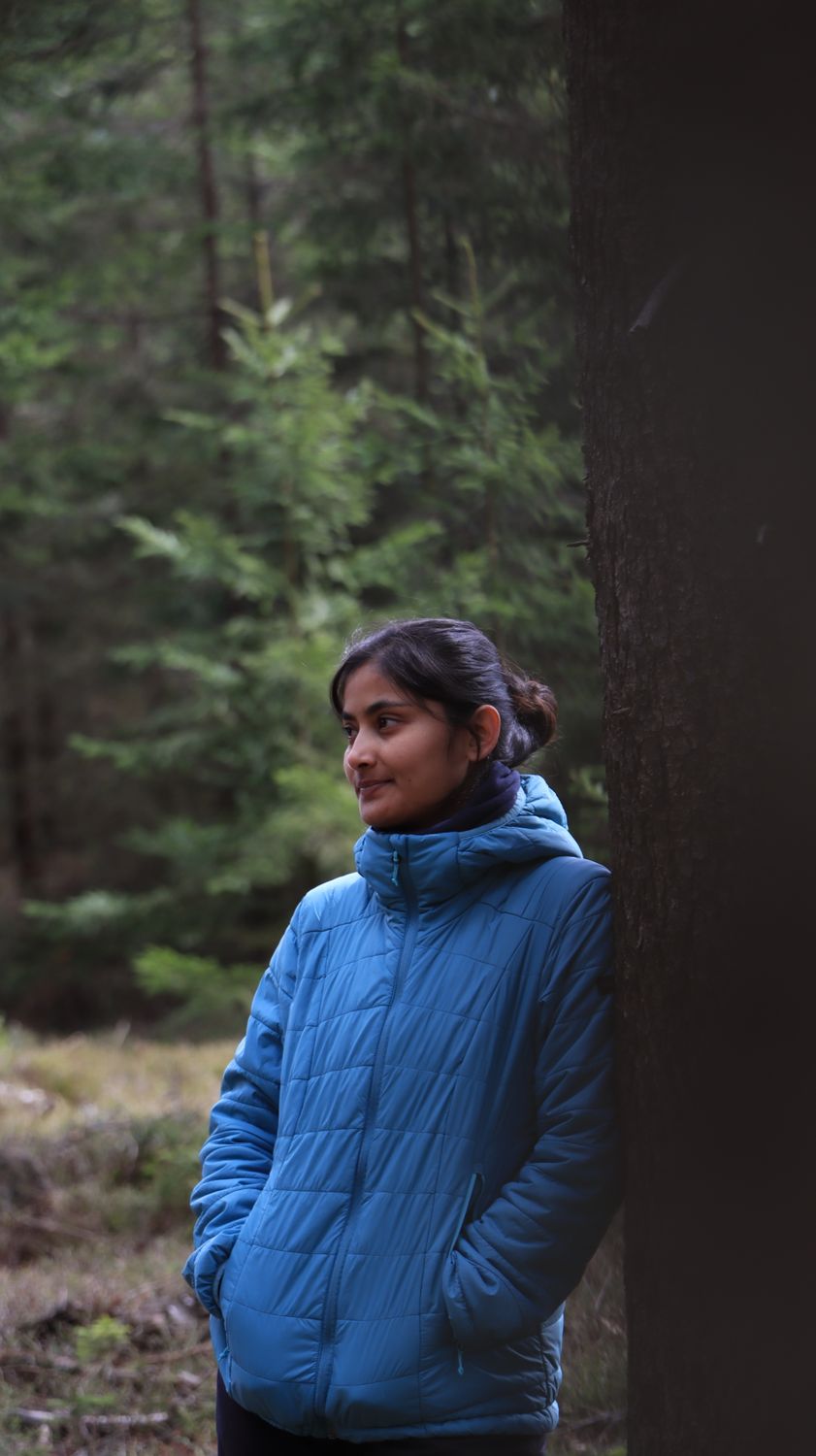 A woman in a blue jacket standing near a tree · Free Stock Photo