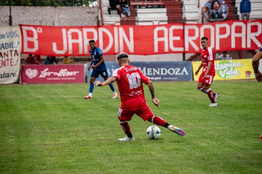 Action-packed soccer game with players in red and blue jerseys on a grassy field.