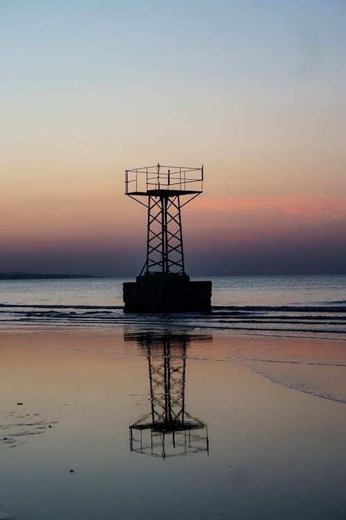 A Silhouetted Tower on the Shore at Sunset 