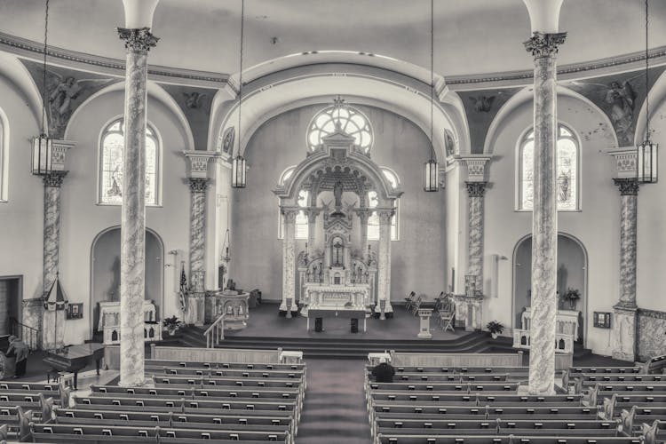 Black And White Photo Of A Man Praying In A Church