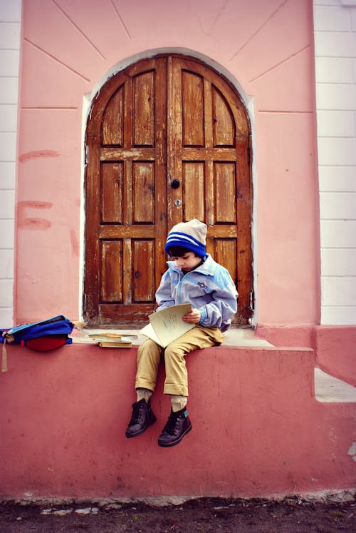 Boy Sitting On Stairs Holding Book 