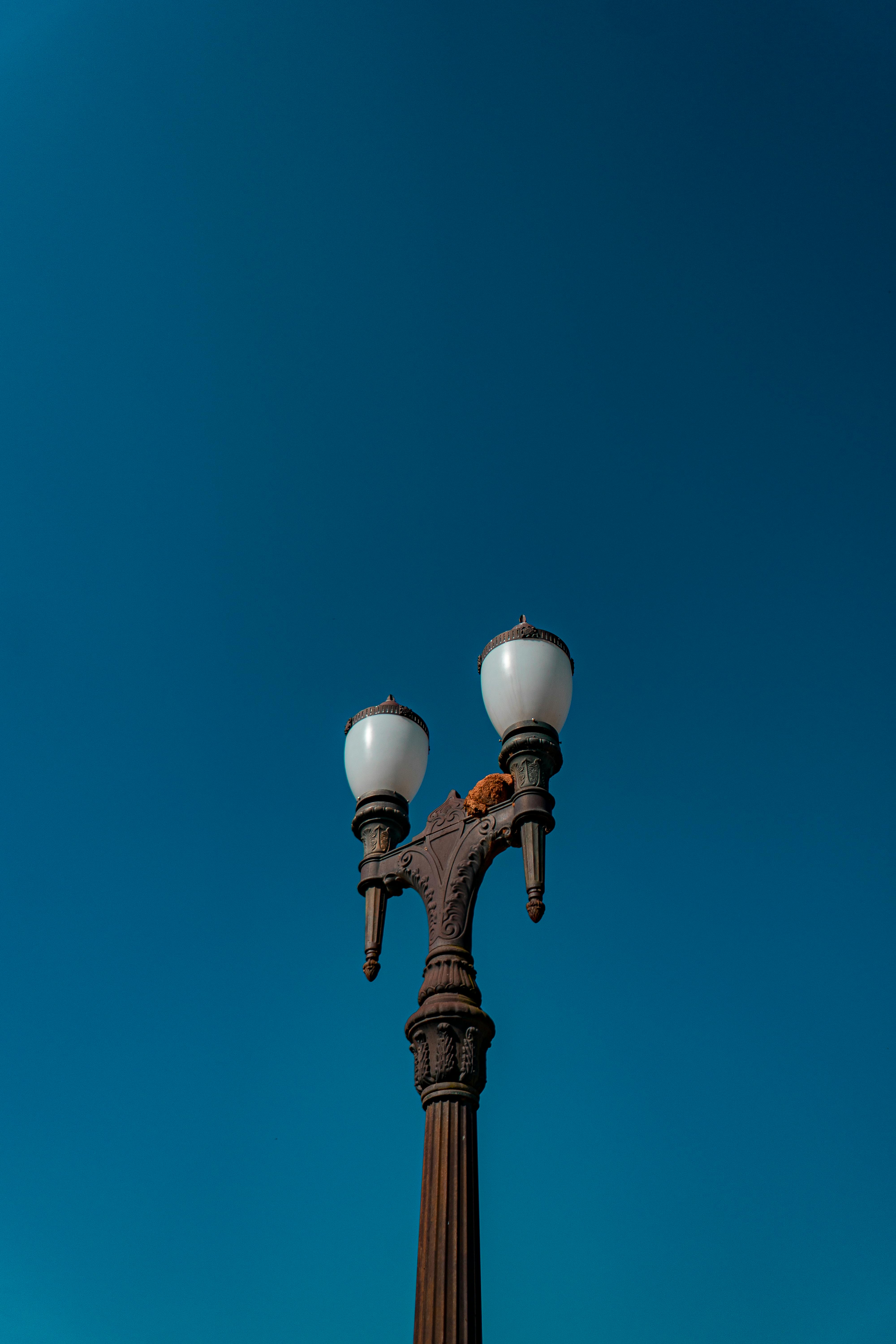 A vintage streetlamp set against a vibrant clear blue sky, captured in a low angle shot.