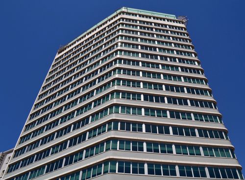 Free Low angle view of a modern office building against clear blue sky. Stock Photo