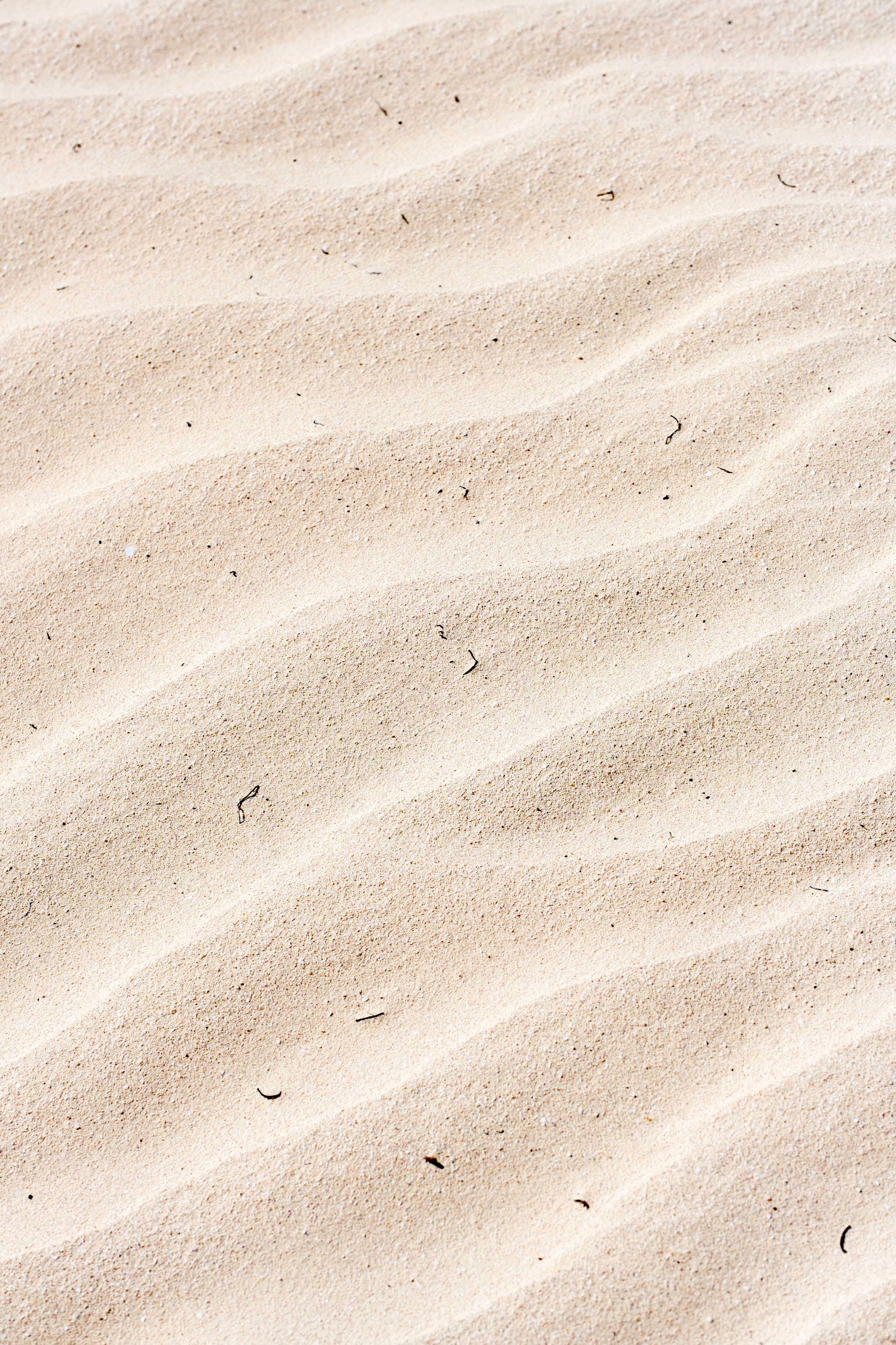 A textured view of sand ripples resembling desert dunes, ideal for background use.