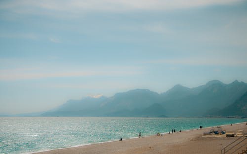A beach with people walking on it and a mountain in the background