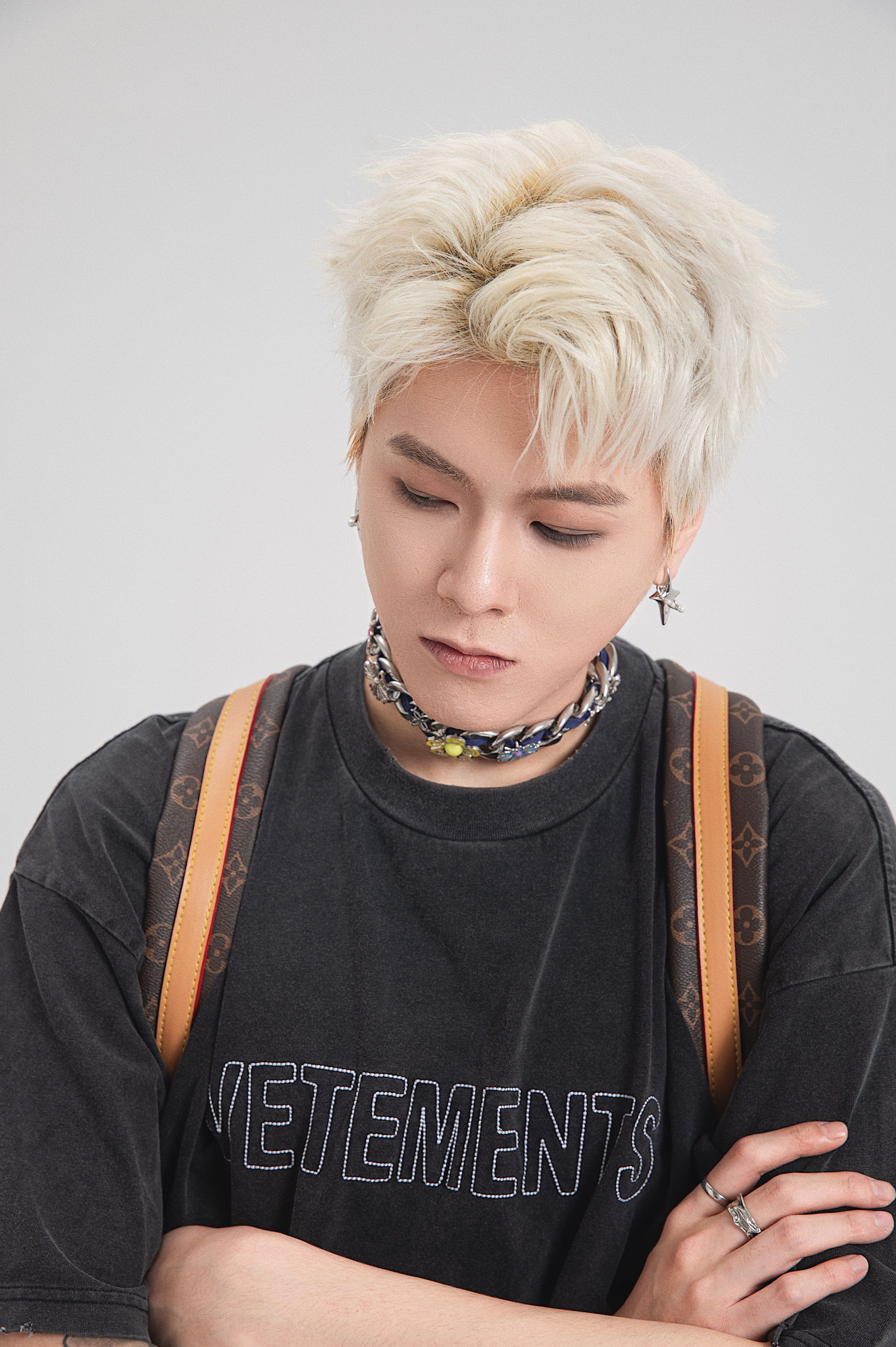 Fashionable young adult with platinum blond hair, posing in streetwear style.