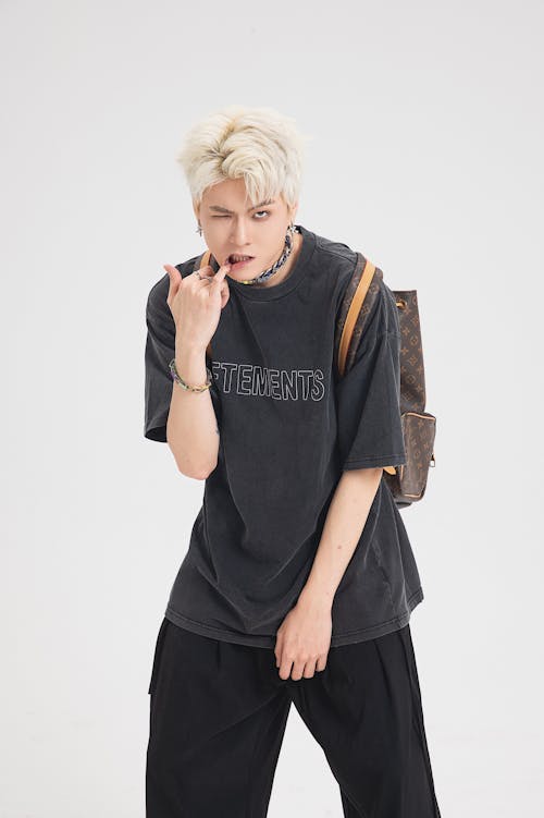 Young Man with Backpack Posing on White Studio Background