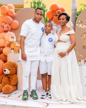 Family posing at a celebration with elegant balloon backdrop and decorations.