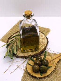 A glass bottle of olive oil beside fresh olives — Laura on Pexels