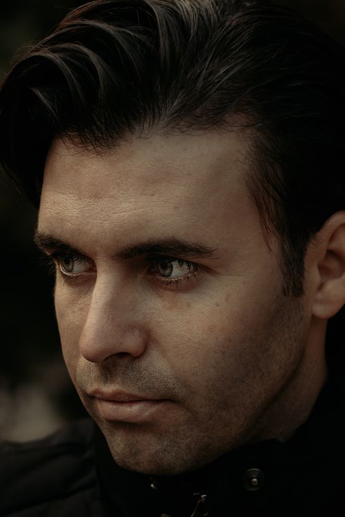 Free Close-up portrait of a contemplative man gazing aside in a moody, natural setting. Stock Photo