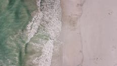 从空中俯瞰，轻柔的海浪拍打沙滩的景象令人惊叹，展现了大自然的美丽