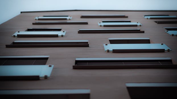 Modern building facade with metal balconies viewed from below, showcasing contemporary urban architecture.
