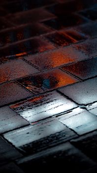 Glimmering city lights reflecting on wet pavement create a moody, abstract urban scene.