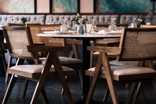 Free Sophisticated restaurant setting featuring stylish wooden chairs, glassware, and a beautifully set table. Stock Photo