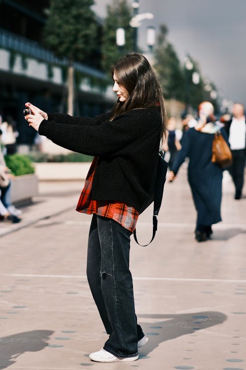 Woman Taking Photo with a Camera on a Sidewalk