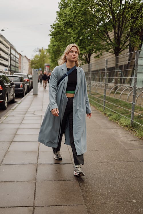 Woman in Coat Walking on Sidewalk in City