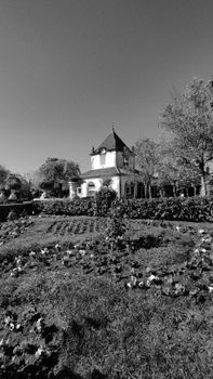 A historic building surrounded by gardens and trees, captured in black and white.