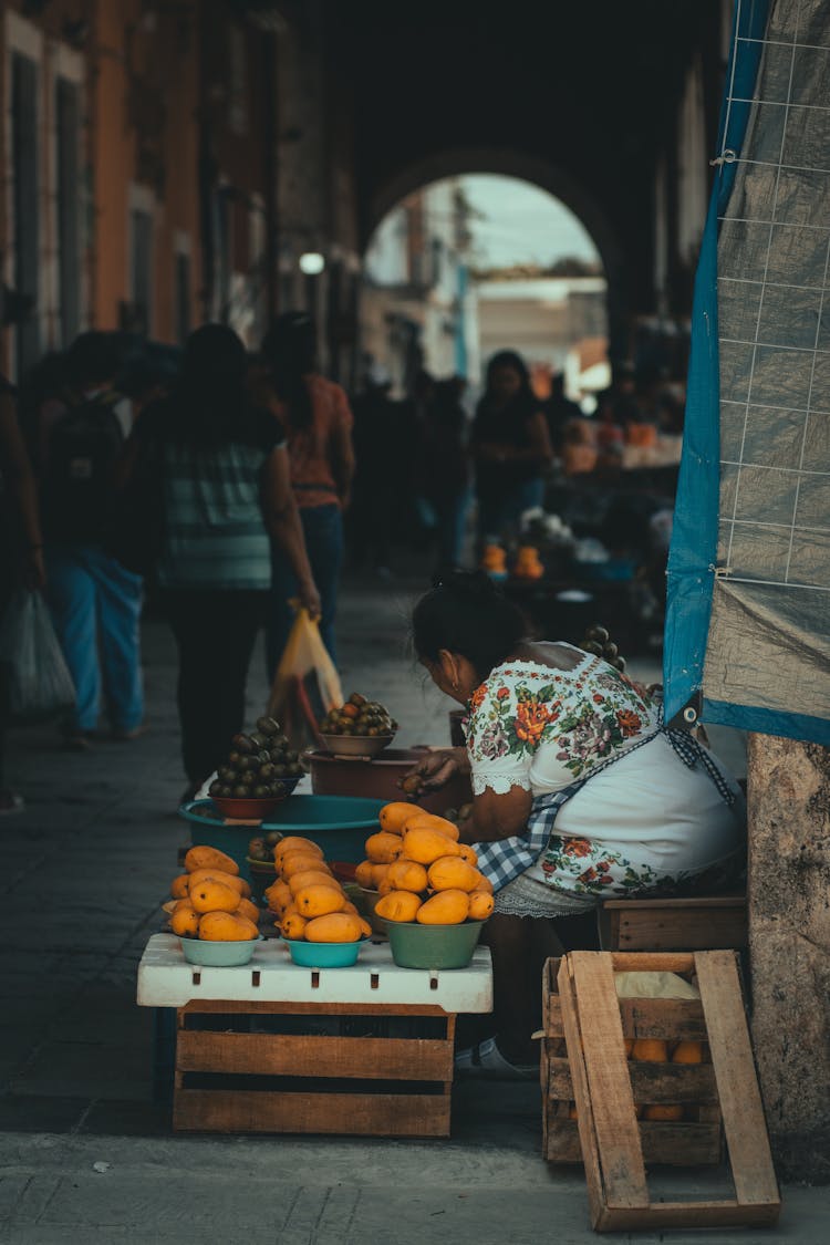 Street Vendors With Fruit Sitting On Pavement In Town