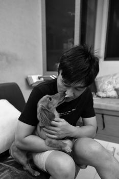 A man shares a heartfelt moment with his Dachshund inside a cozy home.