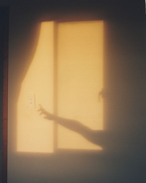 Free Artistic shadow of a hand reaching towards a light switch on a sunlit wall. Stock Photo