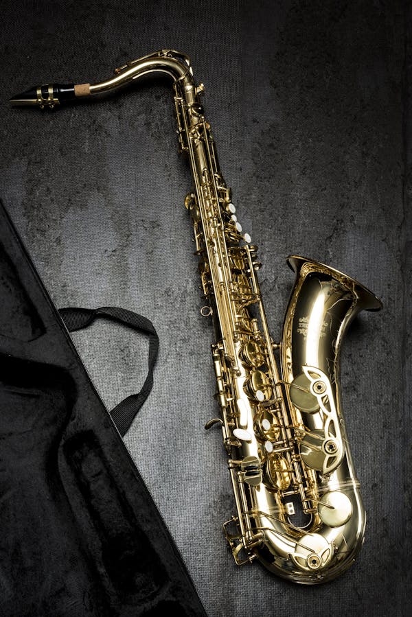Brass Saxophone on Gray Table Near Black Bag