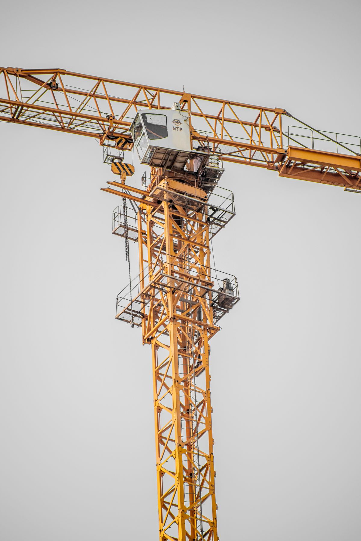 Yellow tower crane at construction site requiring rotation resistant hoist wire rope